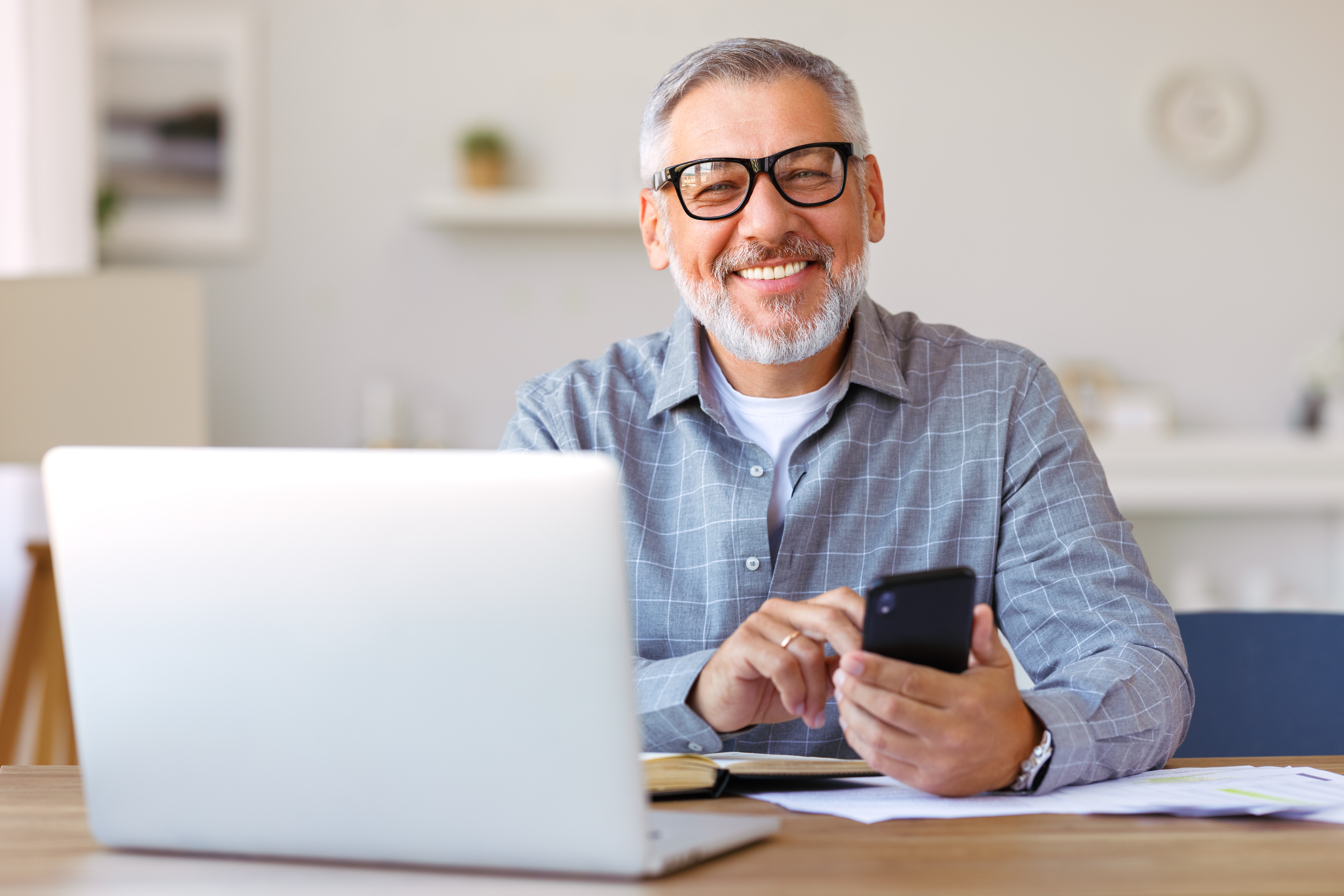 Handsome, smiling older gentleman holding his phone to call his concierge medicine physician