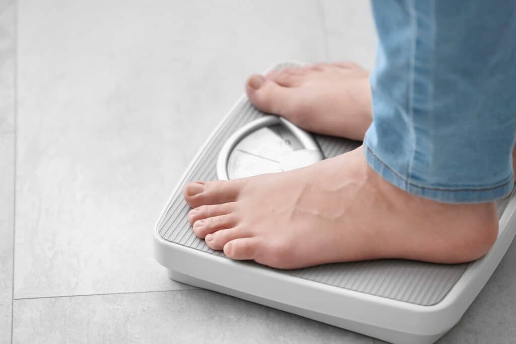 Bare feet standing on a scale, checking progress in a concierge weight loss program