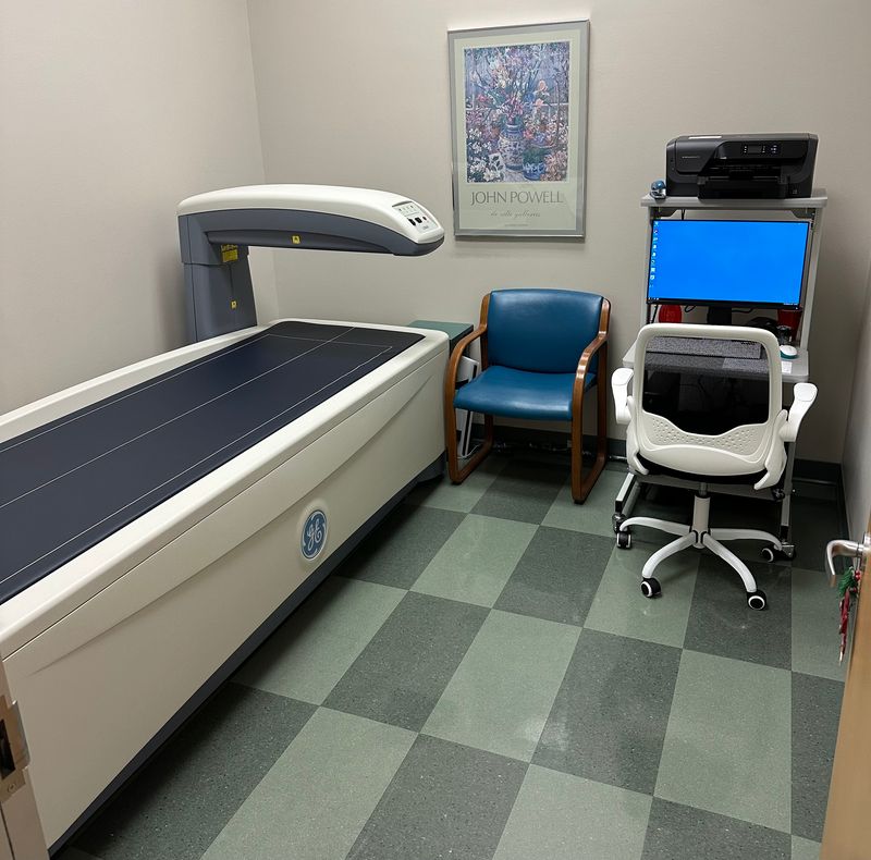 A GE Lunar Prodigy DEXA scan machine, with a viewing monitor by its side in a doctor's office