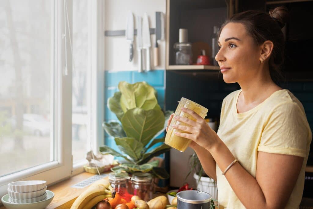 Young woman drinks a smoothie as she thinks about enrolling in concierge medicine