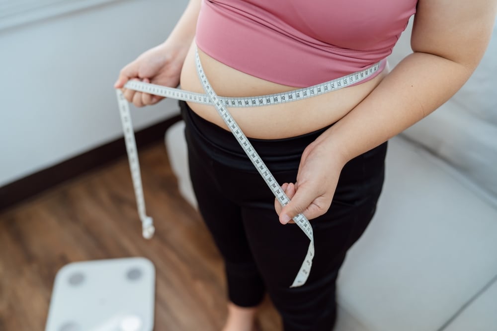 Woman measures her belly using a tape measure in San Antonio as she begins weight management for fat loss